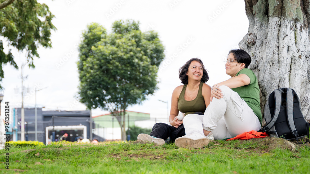 LGBTQ couple relaxing and laughing in a park LGBTQ couple relaxing and laughing in a park