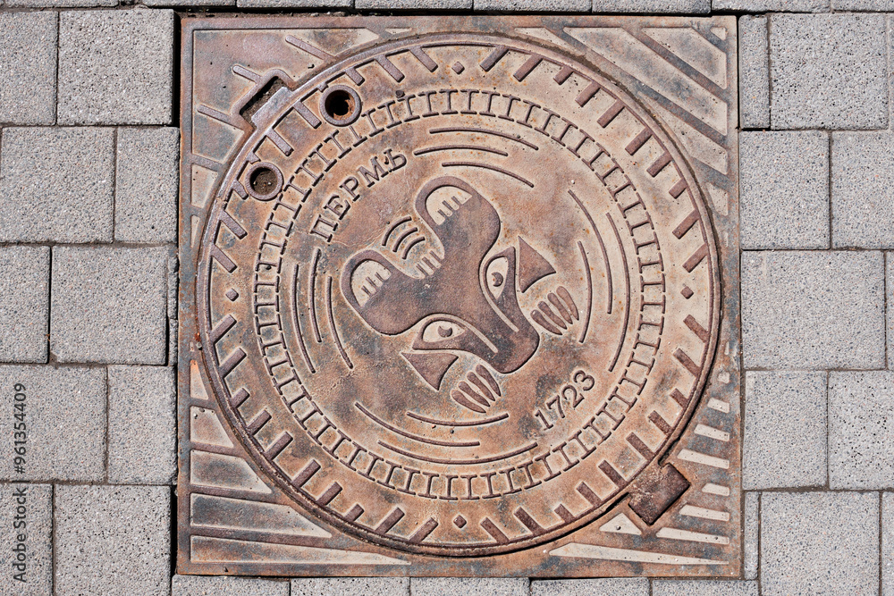 Cast iron round cover for manhole on sidewalk in Perm, Russia. Image of symbol of city bear. Cast iron round cover for manhole on sidewalk in Perm, Russia. Image of symbol of city bear.