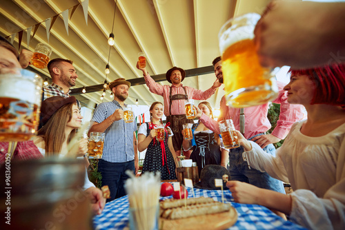 Photography Men in traditional Bavarian clothes cheering group of his friends, people meeting at local pub for beer festival celebration