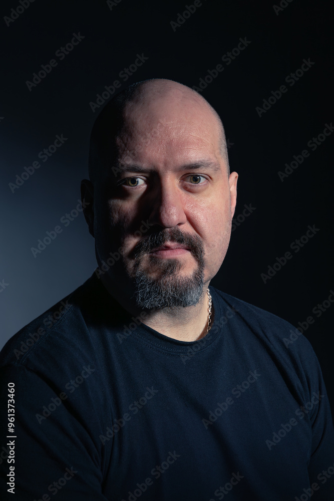 Portrait of a bald mature man with goatee and serious and calm expression, looking at camera on black background. Studio photography. Concept of man, maturity and baldness Portrait of a bald mature man with goatee and serious and calm expression, looking at camera on black background. Studio photography. Concept of man, maturity and baldness