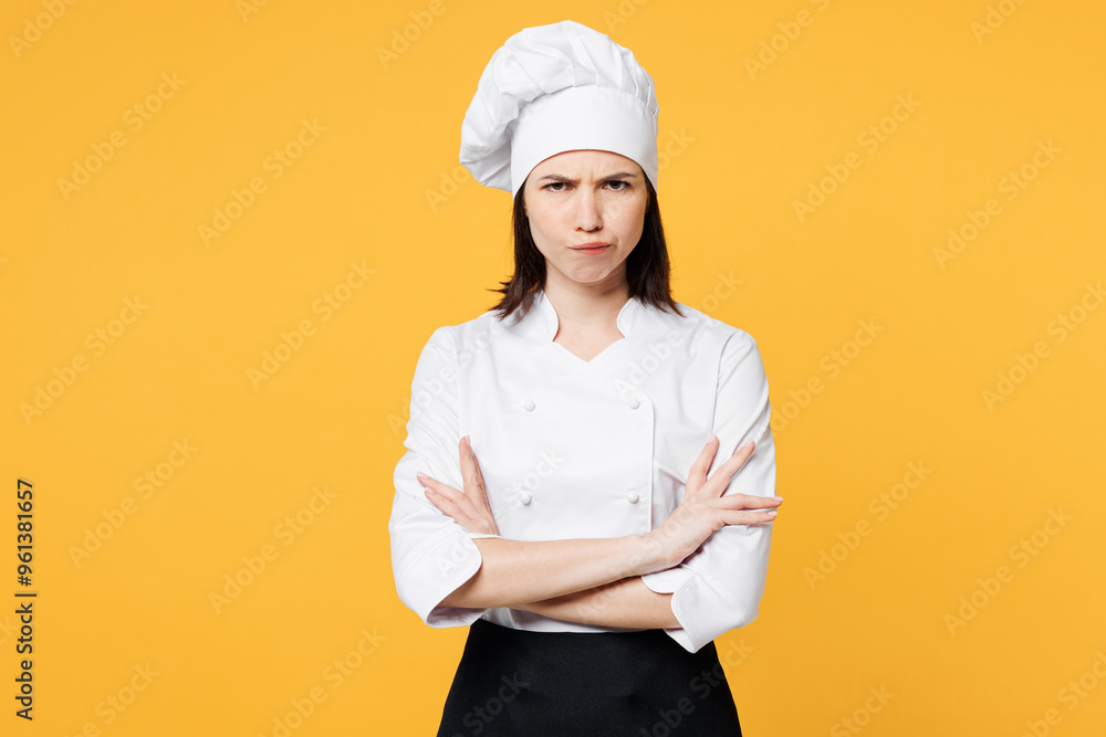 Young frowning sad chef cook baker woman wear white shirt black apron uniform toque chefs hat hold hands crossed folded look camera isolated on plain yellow background studio. Cooking food concept. Young frowning sad chef cook baker woman wear white shirt black apron uniform toque chefs hat hold hands crossed folded look camera isolated on plain yellow background studio. Cooking food concept.