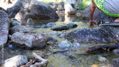 On a hot summer day, a joyful little boy enthusiastically plays in the river, splashing water all around him. He is carefree and enjoying every moment, laughing and having a great time. photo