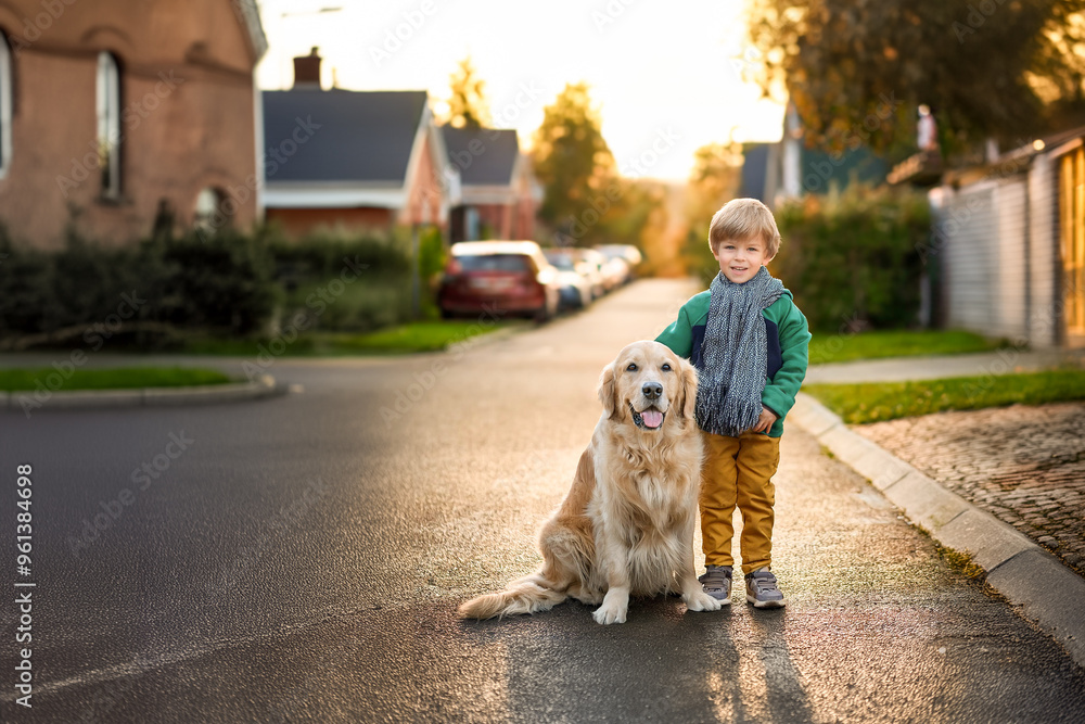 A happy little boy standing next to his friendly golden retriever dog in the street. Best friends. A happy little boy standing next to his friendly golden retriever dog in the street. Best friends.