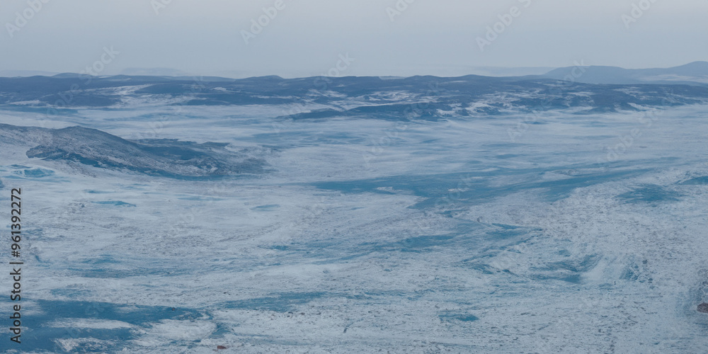 Fototapeta premium Expansive frozen landscape overlooking icy terrain and snow-capped mountains