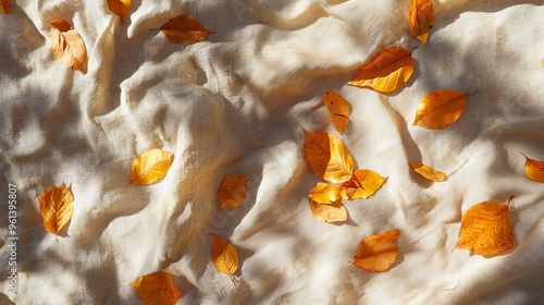 Crumpled linen cloth with fallen autumn leaves and sunlight creating shadows. This creates a beautiful autumn scene, perfect for a business brand template. photo