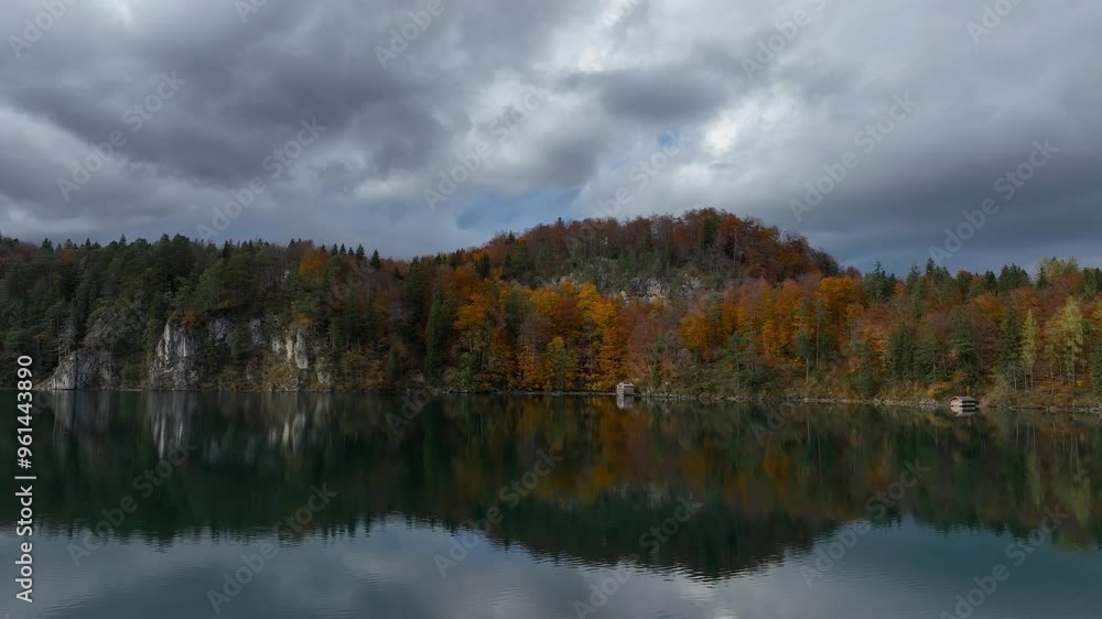 Panoramic view of the Alpsee lake in Autumn trees season and Bavaria Alps in background, beautiful reflections in water Panoramic view of the Alpsee lake in Autumn trees season and Bavaria Alps in background, beautiful reflections in water