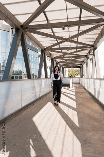 Urban Elegance: Confident Woman Strolling Through Modern Architectural Walkway