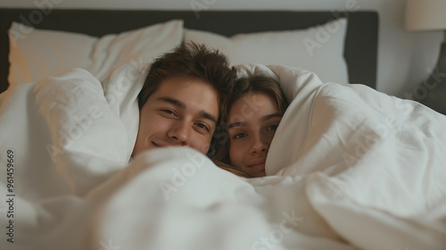 Young couple hugging, teasing and laughing on a white bed. Showing happiness in the morning