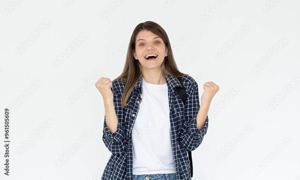 Portrait of ecstatic woman 20s wearing blue shirt clenching fist like rejoicing victory or triumph isolated over white background Portrait of ecstatic woman 20s wearing blue shirt clenching fist like rejoicing victory or triumph isolated over white background