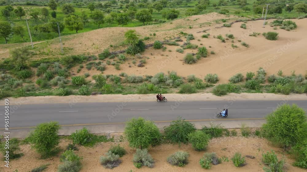 Side view of biker riding bike over the remote road in forest. Aerial view of highway road sides covered by sand and trees. Side view of biker riding bike over the remote road in forest. Aerial view of highway road sides covered by sand and trees.