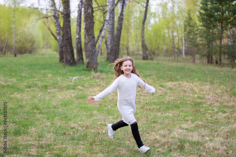 A little girl runs through the spring forest. A child on a walk in the park. A little girl runs through the spring forest. A child on a walk in the park.