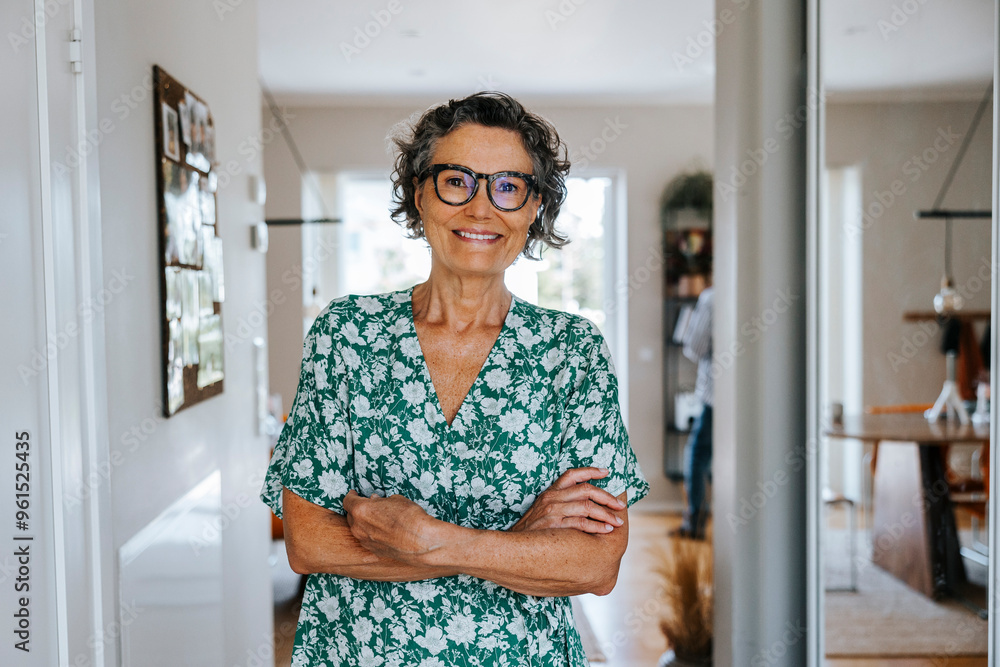 Portrait of smiling senior woman standing with arms crossed at home Portrait of smiling senior woman standing with arms crossed at home