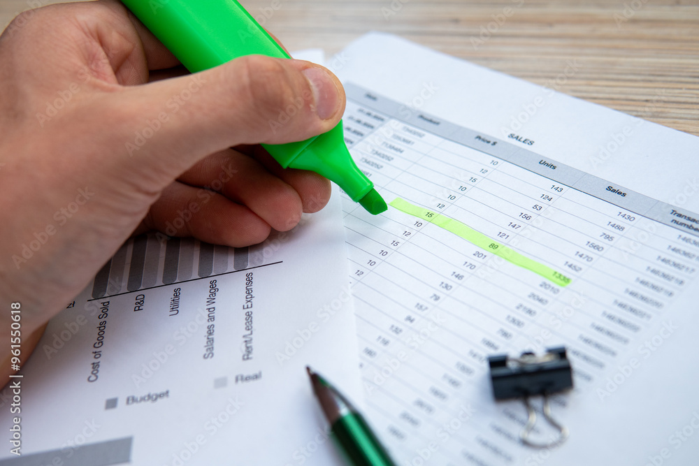 A man highlighting information on financial data, representing the concept of controlling, data analysis, or accounting. A man highlighting information on financial data, representing the concept of controlling, data analysis, or accounting.