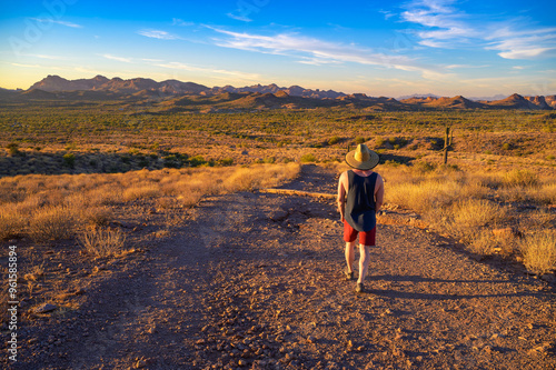 Hiker in a straw hat walking in Lost Dutchman State Park, Arizona. Photographed at sunset.