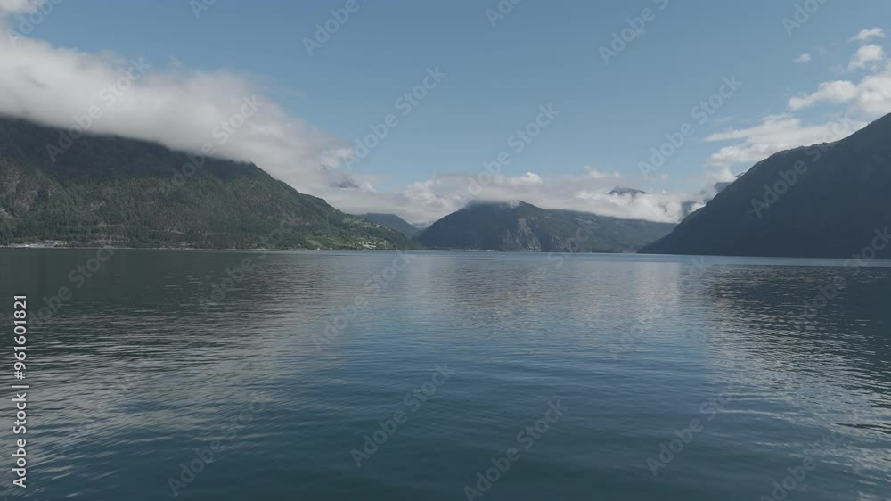 Slowmotion drone shot coming close to the water towards the Fjords in Norway on a sunny and cloudy day with mountains and green in the background and reflecting water LOG Slowmotion drone shot coming close to the water towards the Fjords in Norway on a sunny and cloudy day with mountains and green in the background and reflecting water LOG