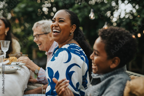 Cheerful mid adult woman having fun with male family members at lunch party photo