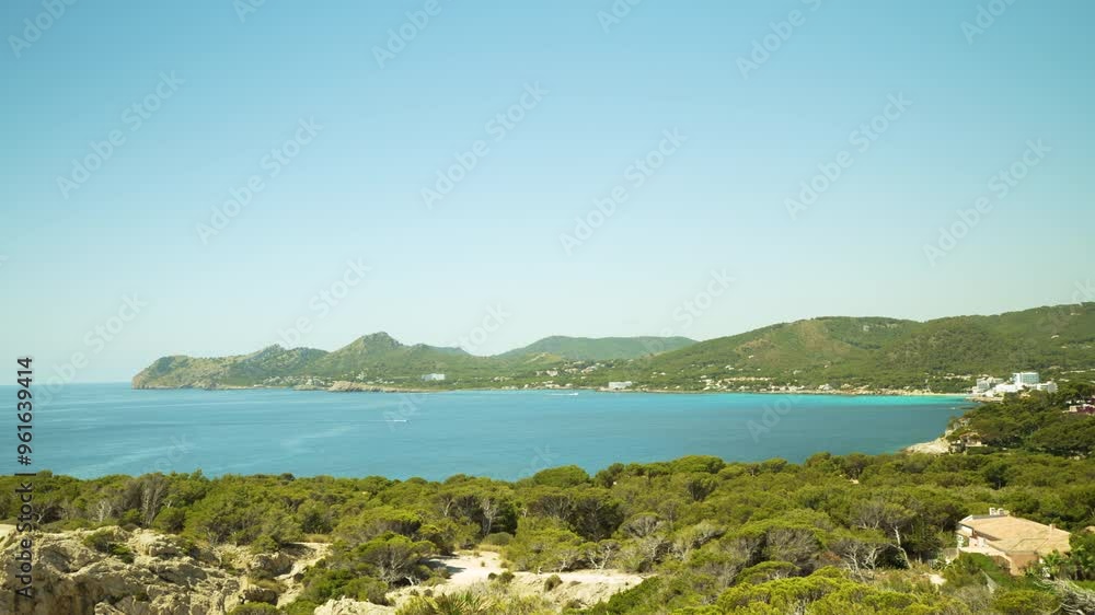 A panoramic view of the eastern coastline of Mallorca, featuring lush green landscapes, serene blue waters, and rolling hills under a clear sky. This image captures the natural beauty and tranquility A panoramic view of the eastern coastline of Mallorca, featuring lush green landscapes, serene blue waters, and rolling hills under a clear sky. This image captures the natural beauty and tranquility