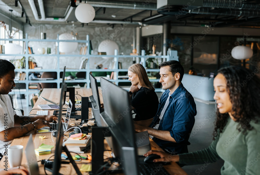 Male and female programmers coding while sitting in tech startup office
