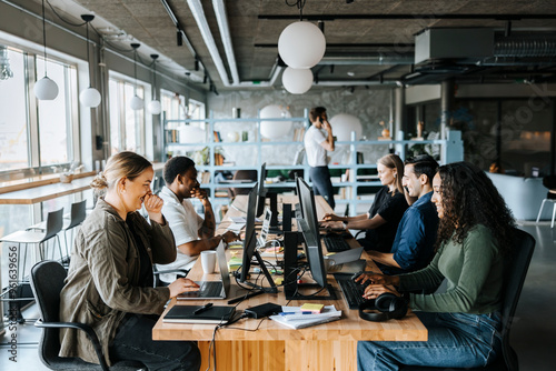 Happy male and female programmers coding while sitting in tech startup office