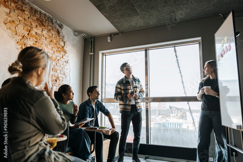 Young female programmer taking team meeting in tech startup office photo