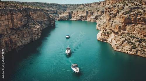 Three boats glide through a stunning canyon waterway surrounded by rocky cliffs.