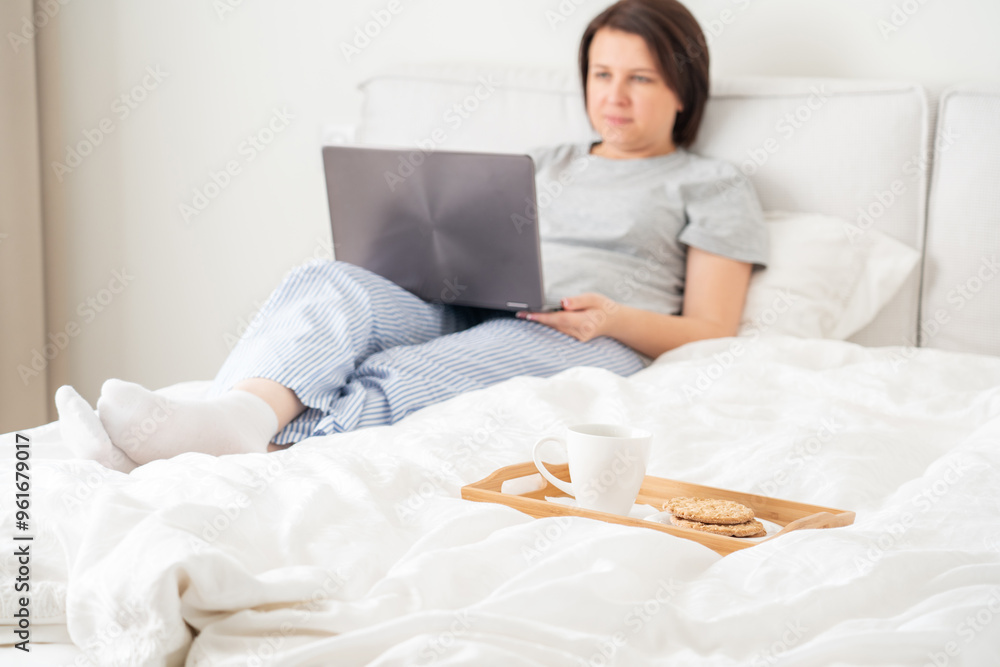 Woman in bed with laptop and breakfast Woman in bed with laptop and breakfast