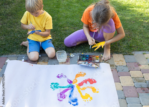 children playing with paints, making footprints and handprints on paper. creative freedom. Interesting fun childhood. Colorful multi-colored prints of children's painted feet photo