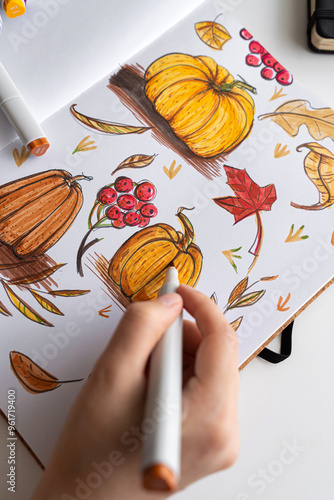 Hand holding marker while drawing autumn illustration