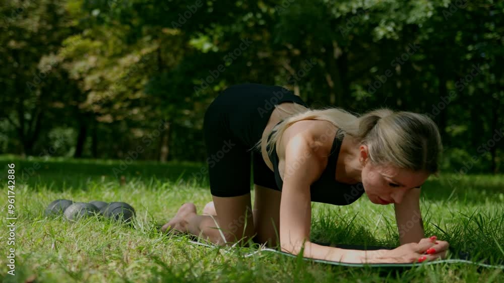 Young slender and pretty woman doing plank in the garden, girl exercise on mat with dumbbells. Concept of sport and healthy lifestyle. Young slender and pretty woman doing plank in the garden, girl exercise on mat with dumbbells. Concept of sport and healthy lifestyle.