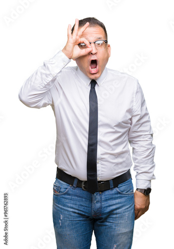 Middle age bussines arab man wearing glasses over isolated background doing ok gesture shocked with surprised face, eye looking through fingers. Unbelieving expression.