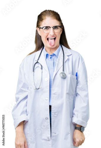 Middle age mature doctor woman wearing medical coat over isolated background sticking tongue out happy with funny expression. Emotion concept.