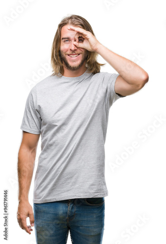 Young handsome man with long hair over isolated background doing ok gesture with hand smiling, eye looking through fingers with happy face.