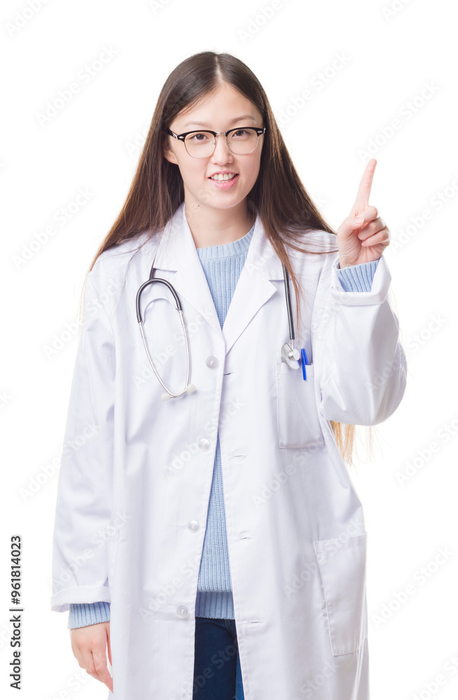 Young Chinese doctor woman over isolated background showing and pointing up with finger number one while smiling confident and happy. Young Chinese doctor woman over isolated background showing and pointing up with finger number one while smiling confident and happy.