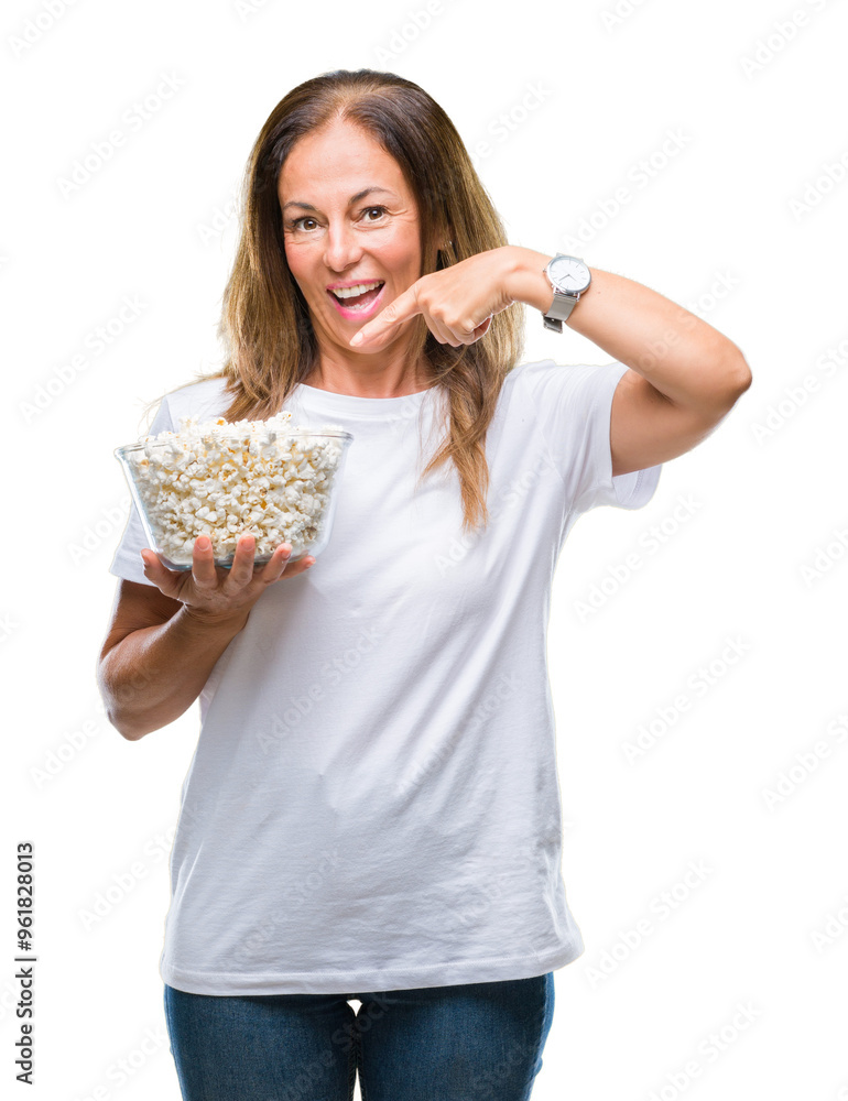 Middle age hispanic woman eating popcorn over isolated background very happy pointing with hand and finger Middle age hispanic woman eating popcorn over isolated background very happy pointing with hand and finger