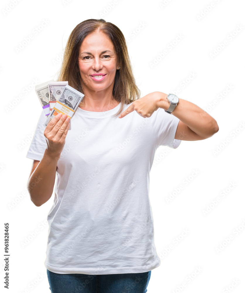 Middle age hispanic woman holding bunch of dollars over isolated background with surprise face pointing finger to himself Middle age hispanic woman holding bunch of dollars over isolated background with surprise face pointing finger to himself