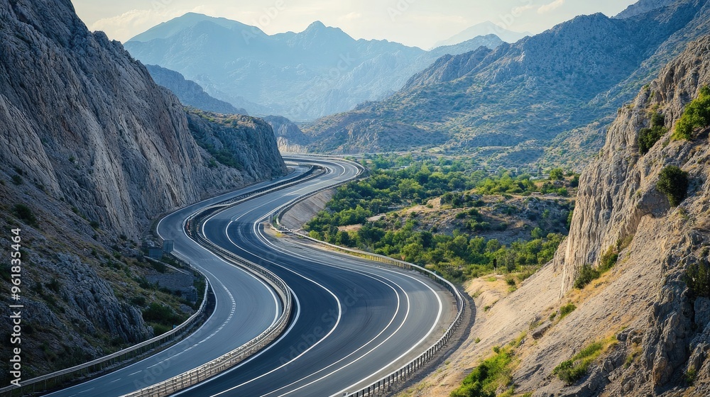 Naklejka premium Scenic view of a motorway winding through mountains or countryside, highlighting the contrast between the road and natural scenery.