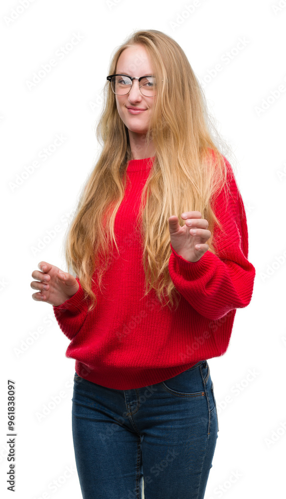 Blonde teenager woman wearing red sweater disgusted expression, displeased and fearful doing disgust face because aversion reaction. With hands raised. Annoying concept. Blonde teenager woman wearing red sweater disgusted expression, displeased and fearful doing disgust face because aversion reaction. With hands raised. Annoying concept.
