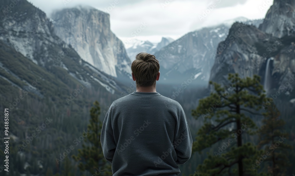 A stunning image of a person in a gray hoodie standing and overlooking a grand and impressive mountain landscape, soaking in the view A stunning image of a person in a gray hoodie standing and overlooking a grand and impressive mountain landscape, soaking in the view
