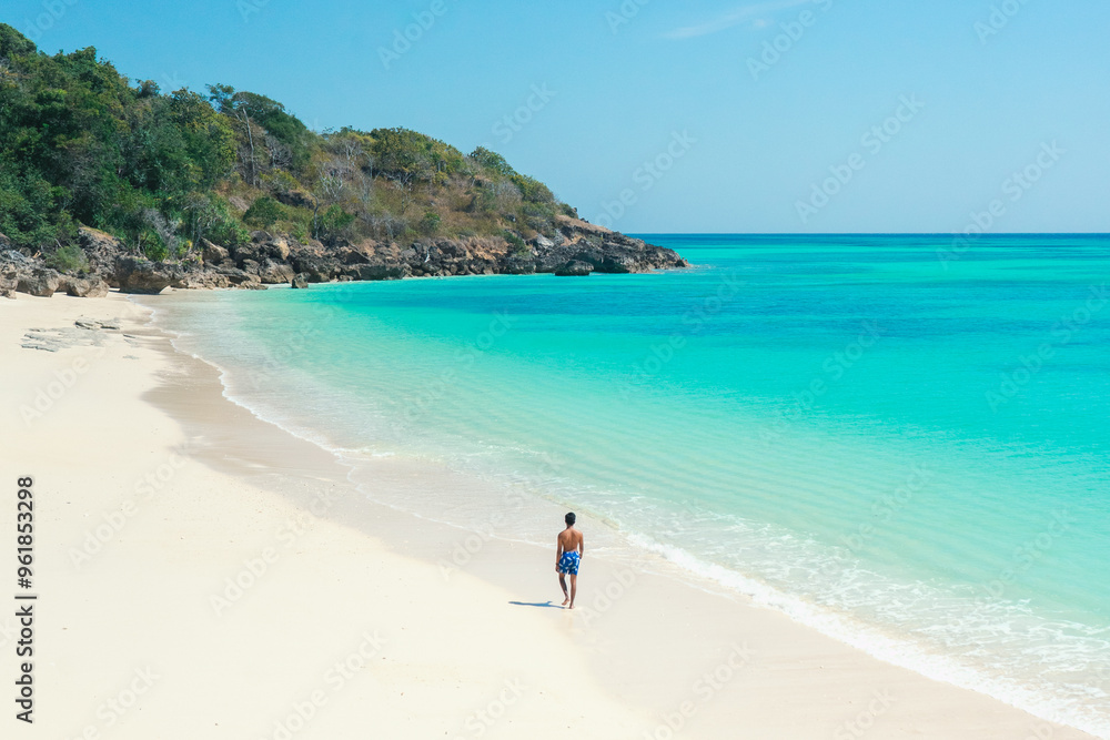 Young asian man walks on the beach in the summer alone on her vacation. summer background and summer holiday concept. Young asian man walks on the beach in the summer alone on her vacation. summer background and summer holiday concept.