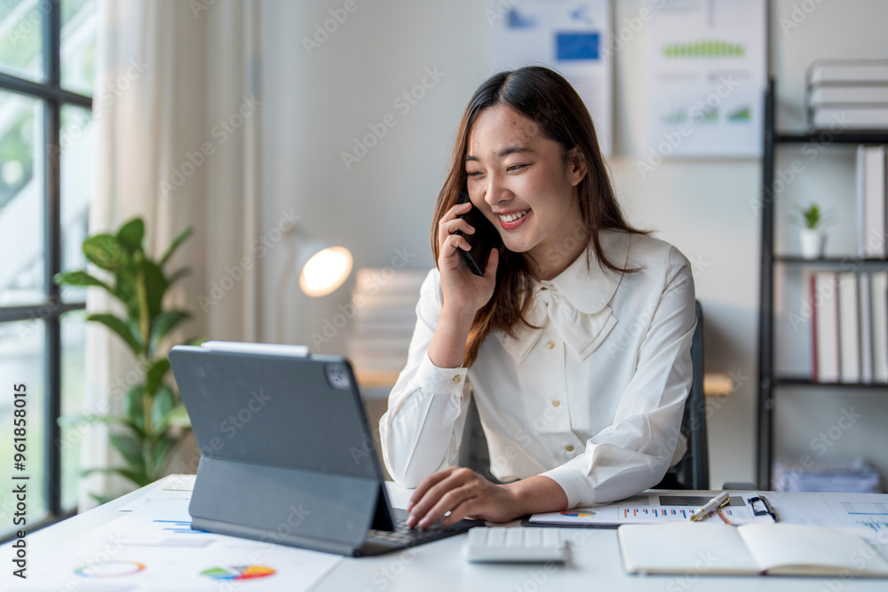 Businesswoman smiling while talking on phone and using tablet in office Businesswoman smiling while talking on phone and using tablet in office