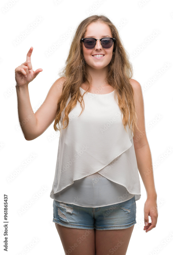 Young blonde woman wearing sunglasses smiling and confident gesturing with hand doing size sign with fingers while looking and the camera. Measure concept. Young blonde woman wearing sunglasses smiling and confident gesturing with hand doing size sign with fingers while looking and the camera. Measure concept.