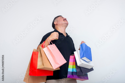 A tired and exasperated middle-aged man struggling to carry multiple shopping bags bought by his wife. Isolated on a white background. photo