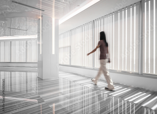 A woman walking through the stripe lines corridor with morning light in the office