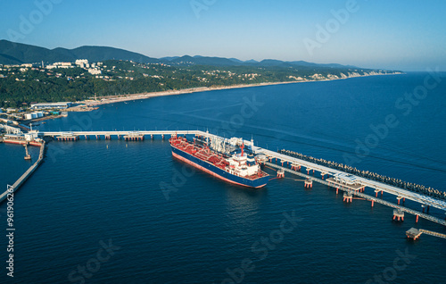 Aerial view of a large oil tanker docked at a pier in the port in process of loading.