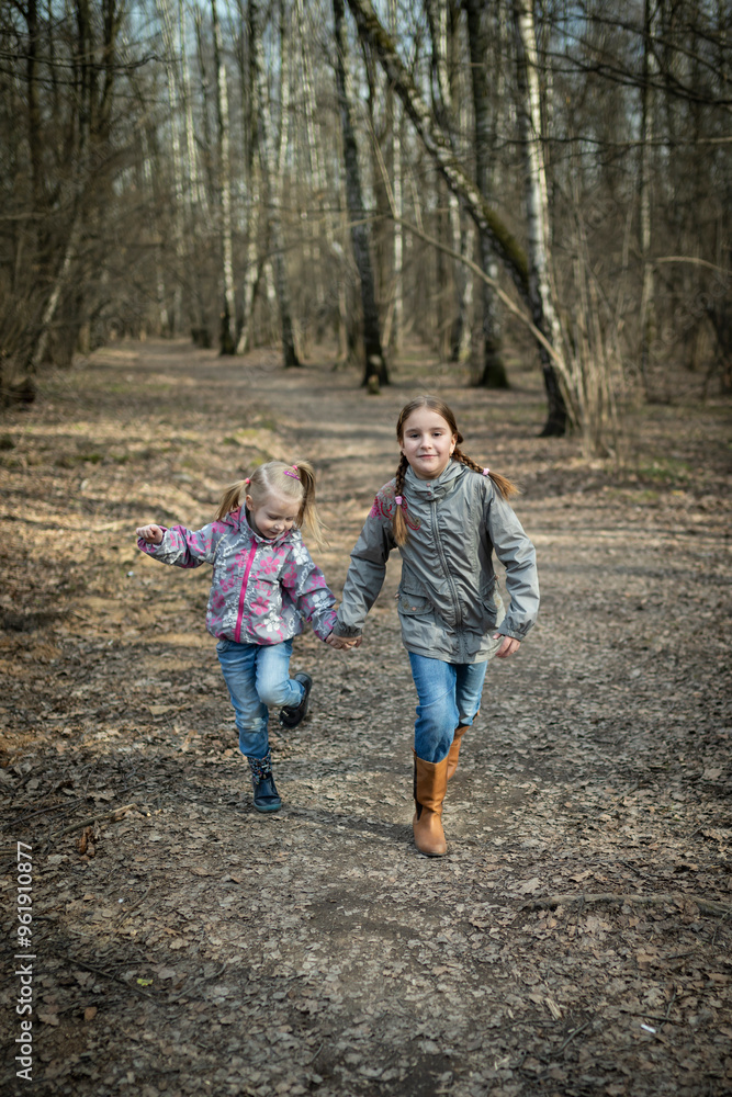 Little girls playing in the forest during the day on a beautiful autumn day. Concept of sisterhood and relationships Little girls playing in the forest during the day on a beautiful autumn day. Concept of sisterhood and relationships