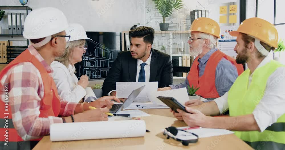 Man main engineer discussing working questions together with professional diverse man and woman team of engineers in meeting room Man main engineer discussing working questions together with professional diverse man and woman team of engineers in meeting room