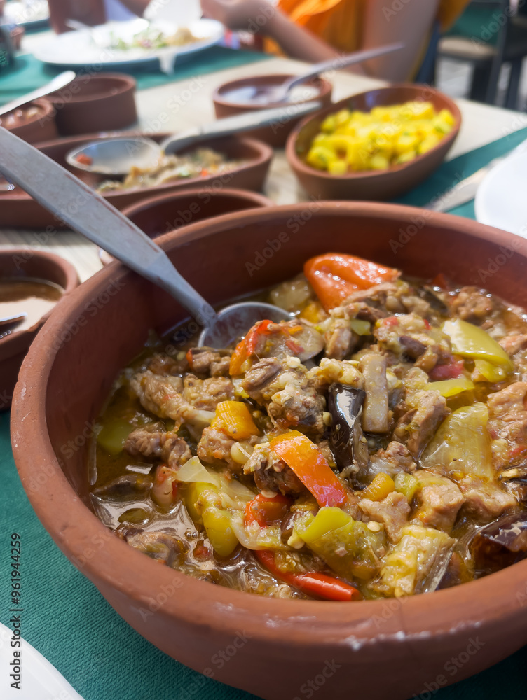 Stewed lamb with eggplant and green pepper in a ceramic bowl on the table during lunch. Homemade dishes. The concept of traditional Turkish cuisine. Vertical orientation. Stewed lamb with eggplant and green pepper in a ceramic bowl on the table during lunch. Homemade dishes. The concept of traditional Turkish cuisine. Vertical orientation.