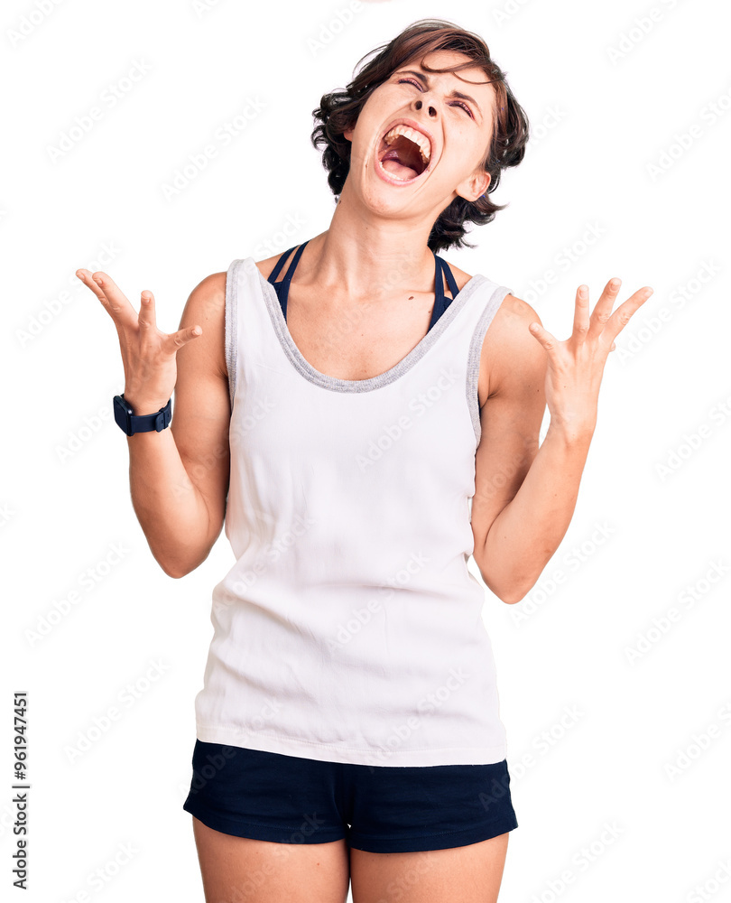 Beautiful young woman with short hair wearing casual sport clothes crazy and mad shouting and yelling with aggressive expression and arms raised. frustration concept. Beautiful young woman with short hair wearing casual sport clothes crazy and mad shouting and yelling with aggressive expression and arms raised. frustration concept.
