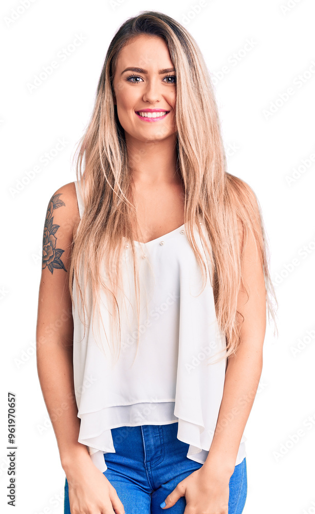 Young beautiful blonde woman wearing sleeveless t-shirt looking positive and happy standing and smiling with a confident smile showing teeth Young beautiful blonde woman wearing sleeveless t-shirt looking positive and happy standing and smiling with a confident smile showing teeth