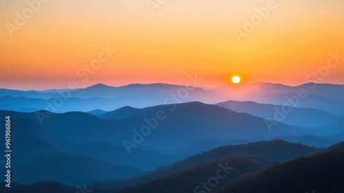 A serene sunset over misty mountains, showcasing layers of blue and orange hues that inspire tranquility and natural beauty.